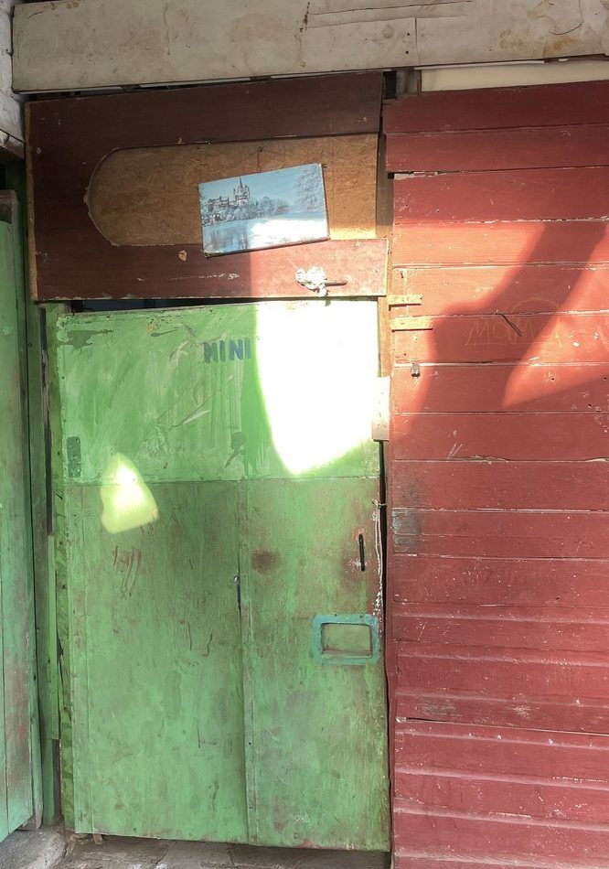 A worn green door beside red painted boards