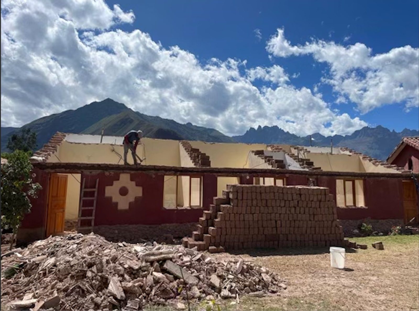 Constructores levantando el techo de un largo edificio de adobe