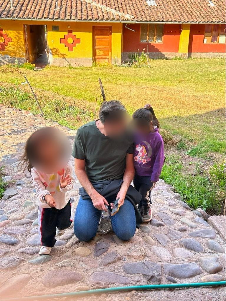 Un adulto arrodillado en un camino de piedra con dos niños